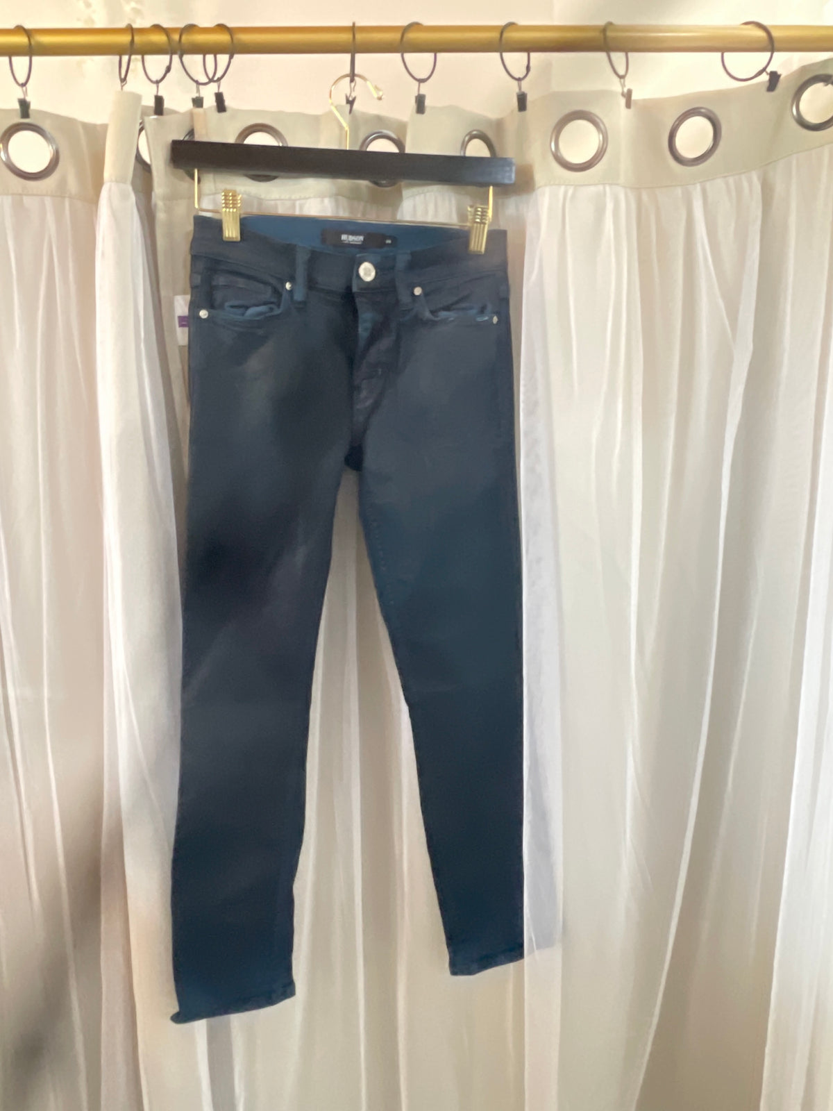 dark wash Hudson skinny jeans suspended on a hanger.