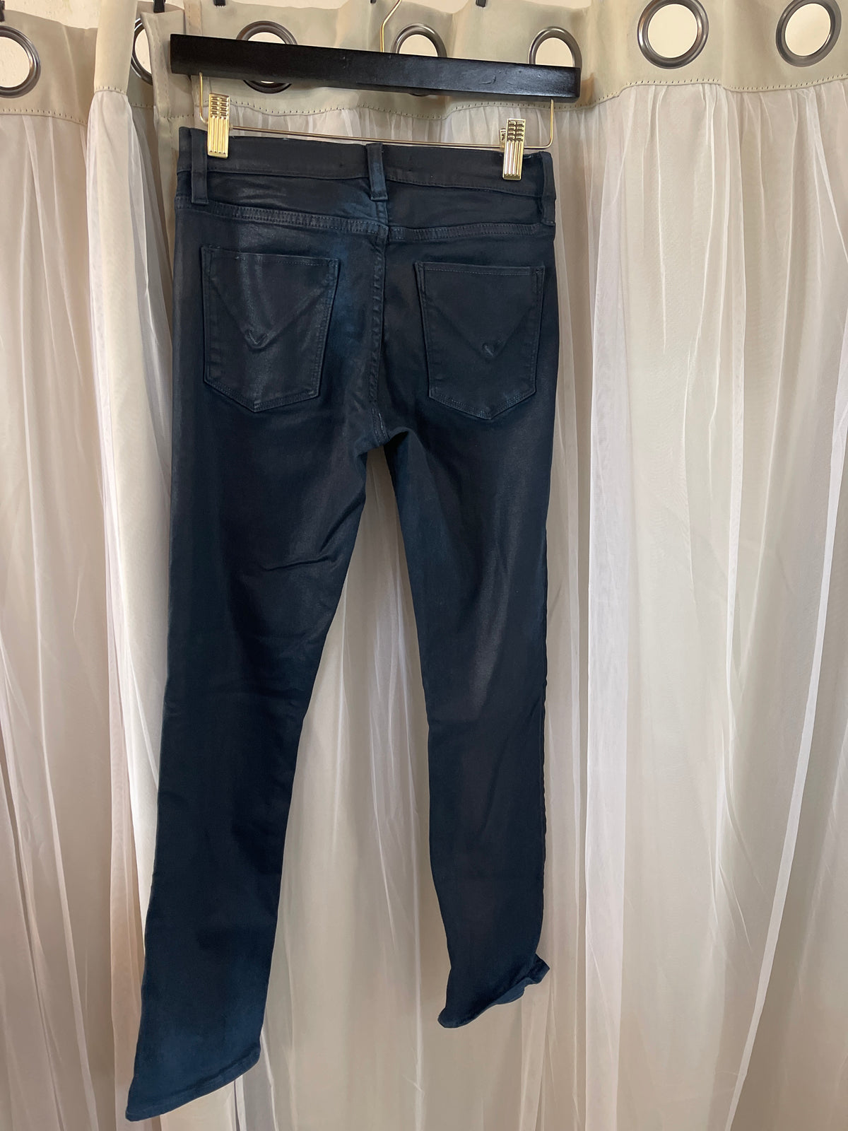 dark wash Hudson skinny jeans suspended on a hanger.