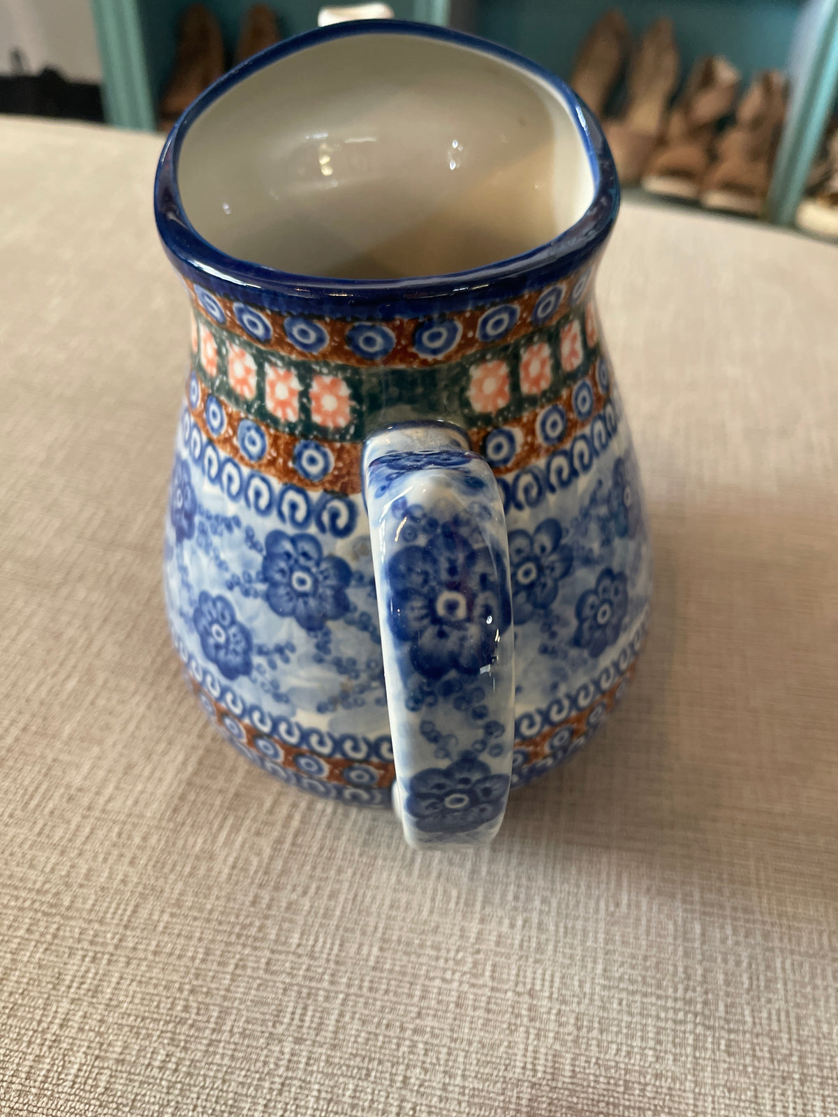 This is a Polish Pottery Unikat watering can pitcher in the "Dancing Blue Poppies" (U57A) pattern, measuring approximately 8.25 inches tall with a 71-ounce capacit