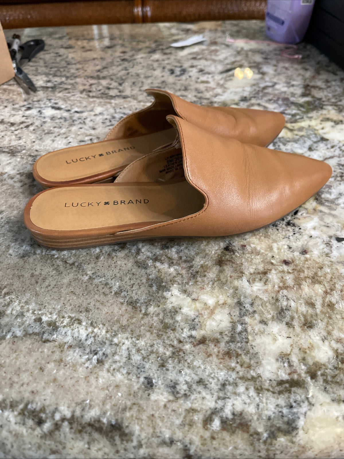 tan pointed-toe leather mules are by Lucky Brand.