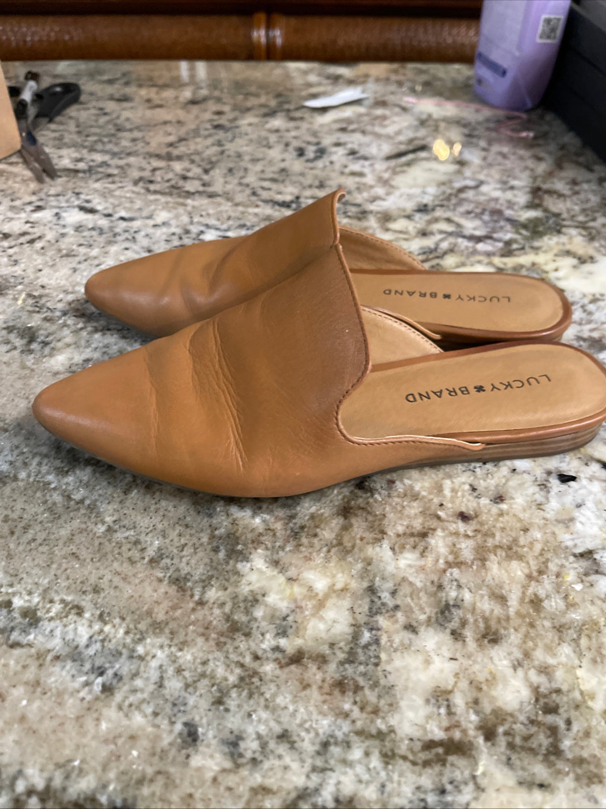tan pointed-toe leather mules are by Lucky Brand.